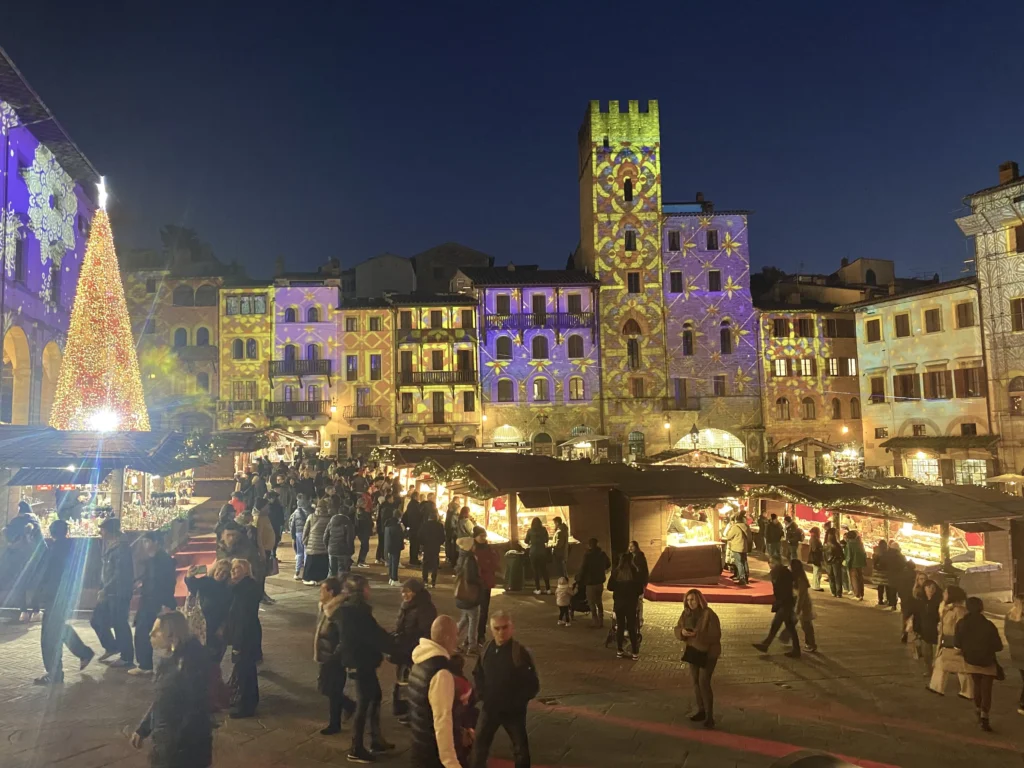 A crowd of people in a square with lights on the side