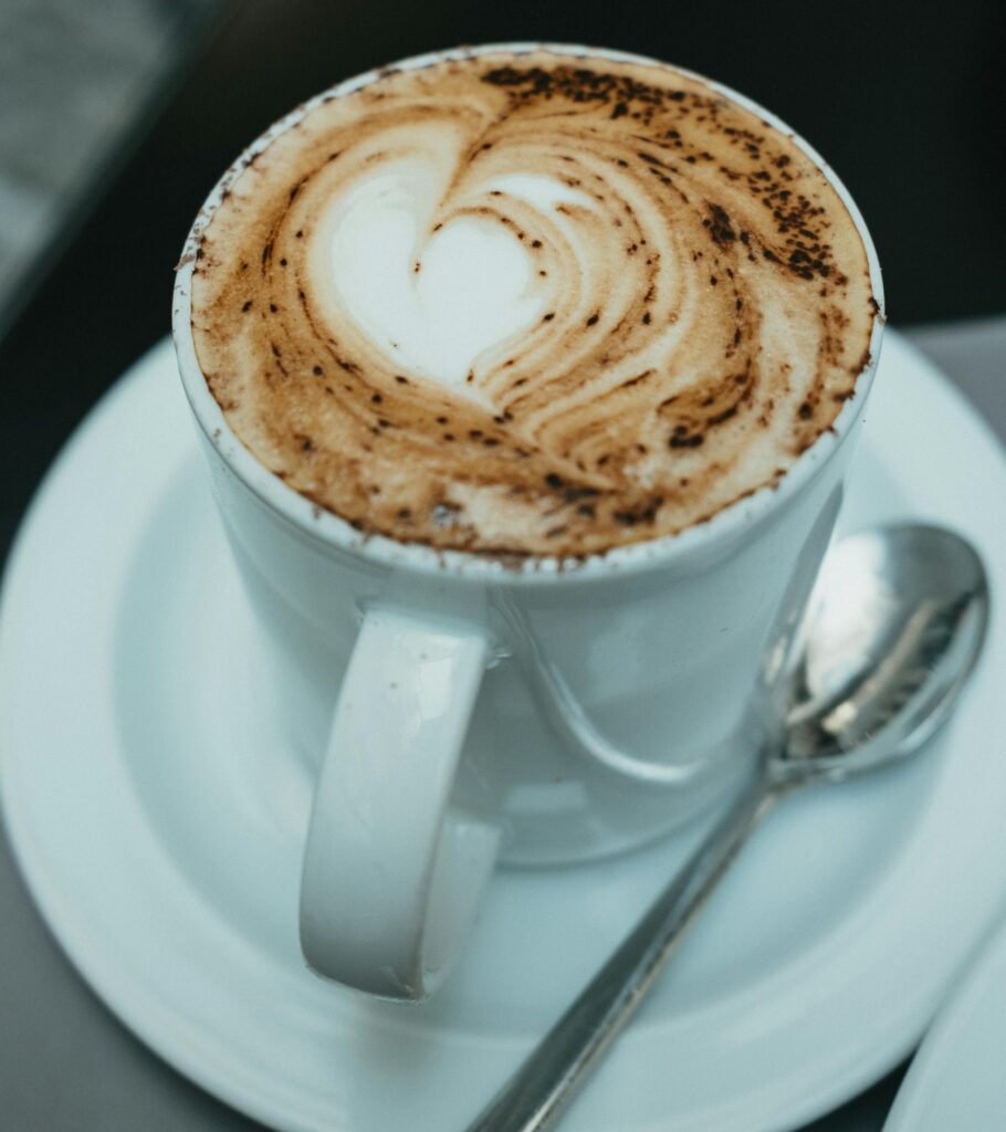 A close-up of a cappuccino with heart-shaped latte art, served in a classic Italian café setting.