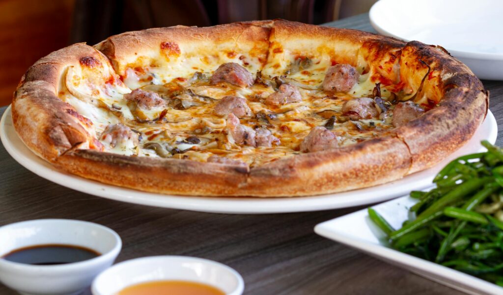 A savory pizza with mushrooms and meatballs served with Asian-style greens.